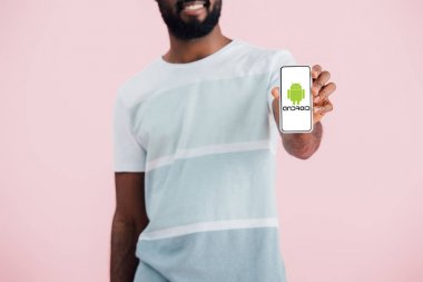 Kiev, Ukrayna - 17 Mayıs 2019: android uygulaması ile akıllı telefon gösteren Afrikalı Amerikalı adamın kırpılmış görünümü, pembe izole 