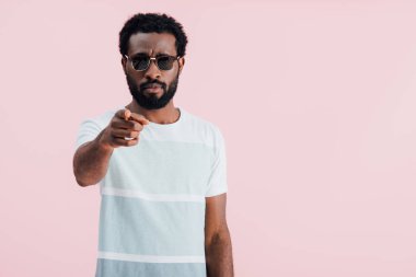 handsome african american of man in sunglasses pointing at you, isolated on pink
