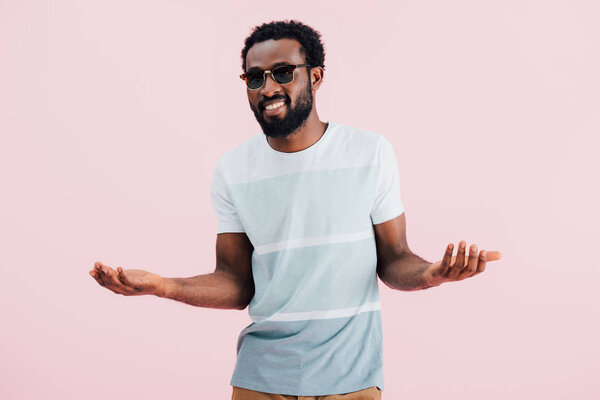 happy african american of man in sunglasses gesturing isolated on pink