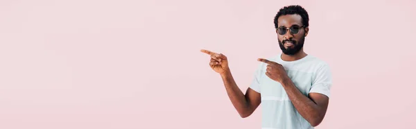 Улыбающийся Африканский Американец Человека Солнцезащитных Очках Указывая Сторону Изолированный Розовый — стоковое фото