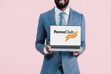 Kiev, Ukrayna - 17 Mayıs 2019: forex kulübü web sitesi ile dizüstü bilgisayar gösteren gülümseyen Afrikalı Amerikalı işadamı kırpılmış görünümü, pembe izole