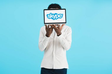 Kiev, Ukrayna - 17 Mayıs 2019: Siyah ibareleri maviye izole edilmiş skype ile dizüstü bilgisayar gösteren Afro-Amerikan adam