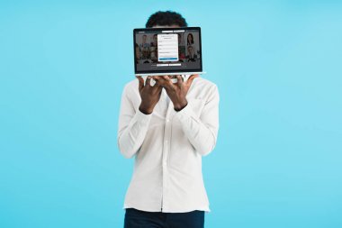 KYIV, UKRAINE - MAY 17, 2019: african american man showing laptop with linkedin  website, isolated on blue clipart