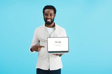 Kiev, Ukrayna - 17 Mayıs 2019: gülümseyen afro-amerikan adam google web sitesi ile dizüstü bilgisayar işaret, mavi izole