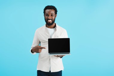 mavi izole boş ekran ile dizüstü bilgisayar işaret gülümseyen afrikalı amerikalı adam