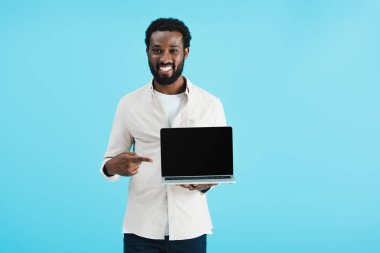 mavi izole boş ekran ile dizüstü bilgisayar işaret gülümseyen afrikalı amerikalı adam