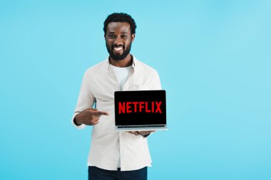 Kiev, Ukrayna - 17 Mayıs 2019: netflix web sitesi ile dizüstü bilgisayar işaret gülümseyen Afrikalı Amerikalı adam, mavi izole