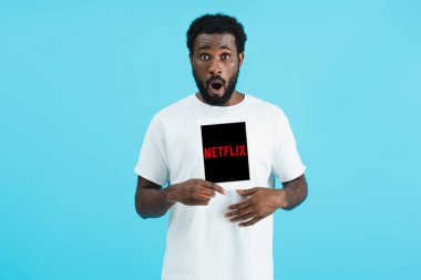 Kiev, Ukrayna - 17 Mayıs 2019: netflix uygulaması ile dijital tablet gösteren şok Afrikalı Amerikalı adam, mavi izole