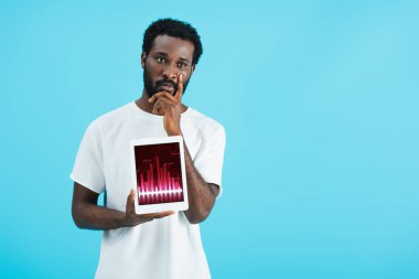 grafik uygulaması ile dijital tablet gösteren düşünceli afrikalı amerikalı adam, mavi izole