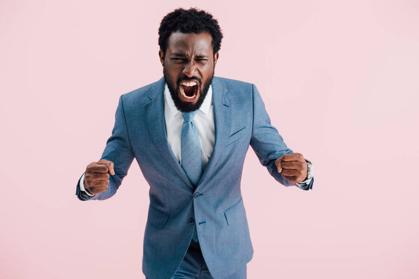 aggressive african american businessman in suit shouting isolated on pink