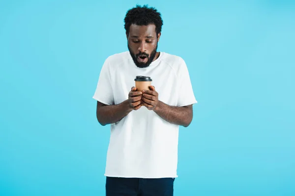 shocked african american man holding coffee to go, isolated on blue