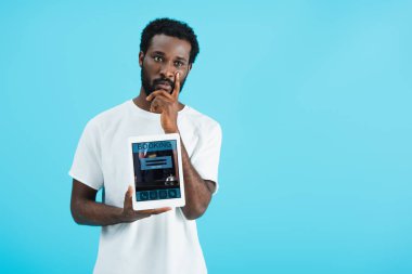 düşünceli afrikalı amerikalı adam rezervasyon uygulaması ile dijital tablet gösteren, mavi izole