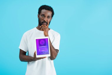 düşünceli afro-amerikan adam alışveriş uygulaması ile dijital tablet gösteren, mavi izole