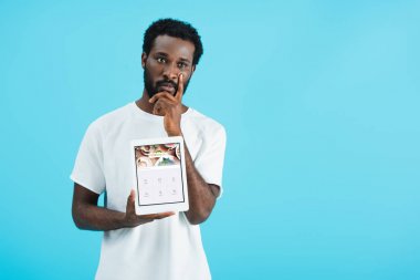 Kiev, Ukrayna - 17 Mayıs 2019: düşünceli afro-amerikan adam foursquare uygulaması ile dijital tablet gösteren, mavi izole