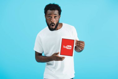 Kiev, Ukrayna - 17 Mayıs 2019: youtube uygulaması ile dijital tablet gösteren afro-amerikan adam şaşırttı, mavi izole