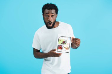 Kiev, Ukrayna - 17 Mayıs 2019: ebay uygulaması ile dijital tablet gösteren afro-amerikan adam şaşırttı, mavi izole
