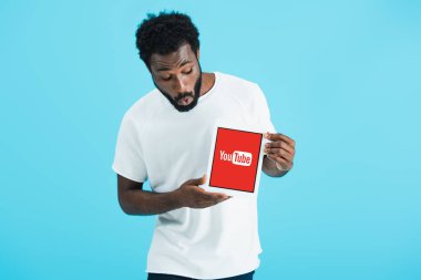 Kiev, Ukrayna - 17 Mayıs 2019: youtube uygulaması ile dijital tablet bakarak şok Afrikalı Amerikalı adam, mavi izole