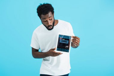 mavi izole rezervasyon uygulaması ile dijital tablet gösteren şok afrikalı amerikalı adam