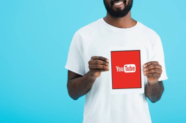 Kiev, Ukrayna - 17 Mayıs 2019: youtube uygulaması ile dijital tablet gösteren Afrikalı Amerikalı adamın kırpılmış görünümü, mavi izole