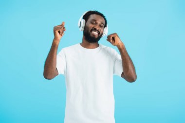 kapalı gözleri dans ve kulaklık ile müzik dinleme ile gülümseyen afrikalı amerikalı adam, mavi izole