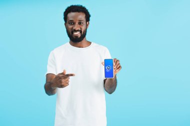 Kiev, Ukrayna - 17 Mayıs 2019: gülümseyen Afro-Amerikan adam shazam uygulaması ile akıllı telefon işaret, mavi izole