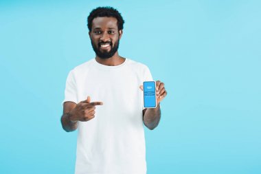 Kiev, Ukrayna - 17 Mayıs 2019: gülümseyen Afrikalı-Amerikalı adam skype uygulaması ile akıllı telefon işaret, mavi izole