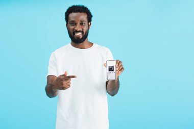 Kiev, Ukrayna - 17 Mayıs 2019: gülümseyen afro-amerikan adam uber uygulaması ile akıllı telefon işaret, mavi izole