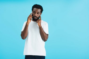 worried african american man talking on smartphone, isolated on blue