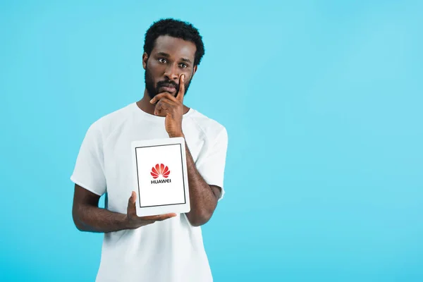 キエフ ウクライナ 2019年5月17日 思慮深いアフリカ系アメリカ人男性がHuaweiアプリでデジタルタブレットを示し 青色で隔離 — ストック写真