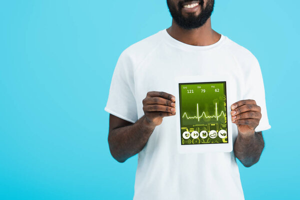 обрезанный вид африканского американец показывает цифровой планшет с приложением здравоохранения, изолированный на синий
