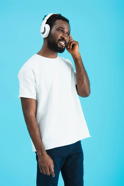 happy african american man listening music with headphones, isolated on blue