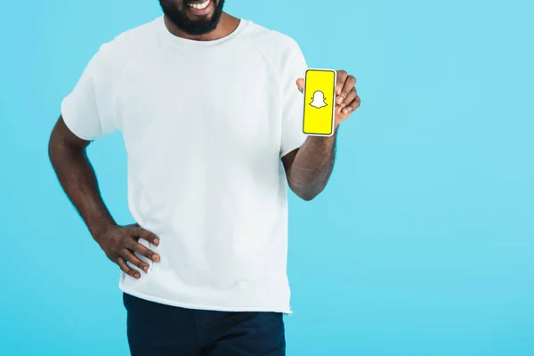 キエフ ウクライナ 2019年5月17日 Snapchatアプリでスマートフォンを示すアフリカ系アメリカ人男性のトリミングビュー 青色で隔離 — ストック写真