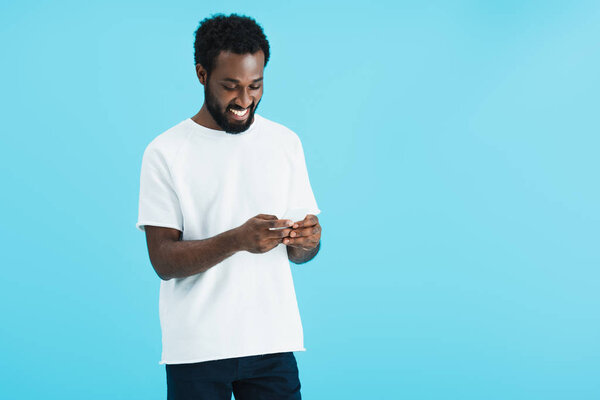 happy african american man using smartphone, isolated on blue