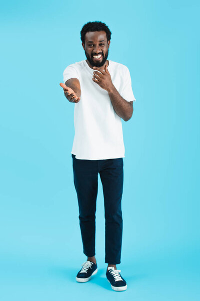 happy african american man laughing and gesturing isolated on blue