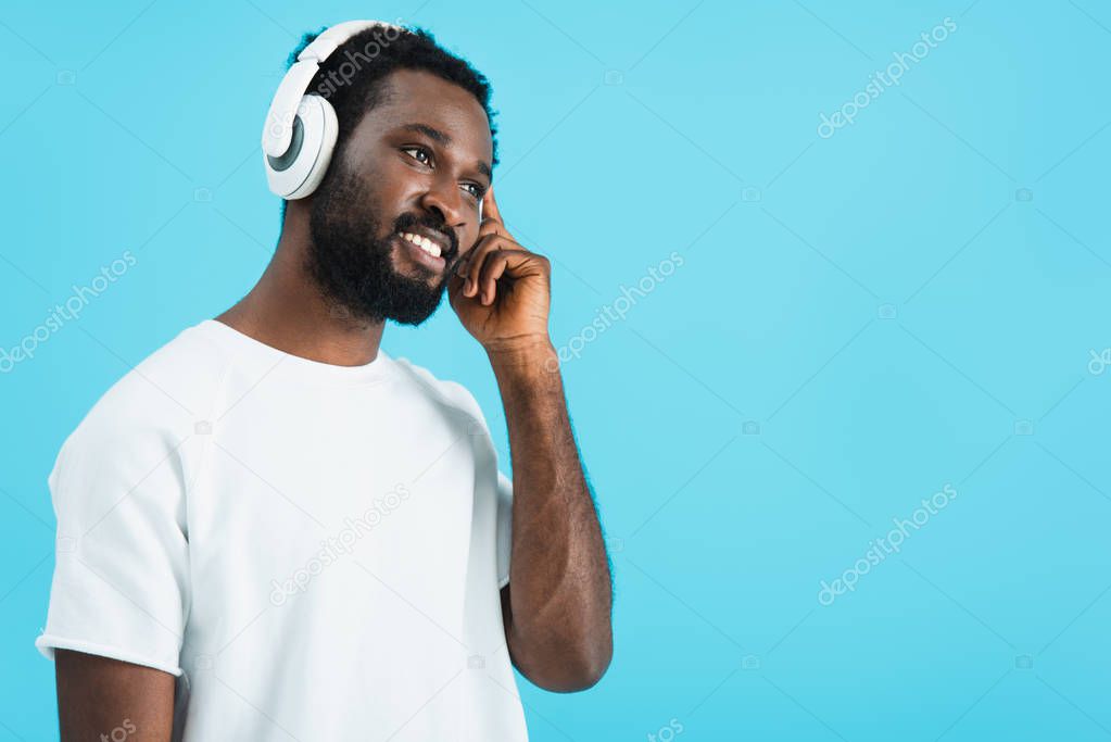 young african american man listening music with headphones, isolated on blue