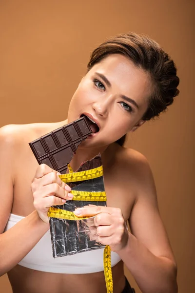 Jovem Com Fita Métrica Amarela Mordendo Barra Chocolate Isolado Bege — Fotografia de Stock