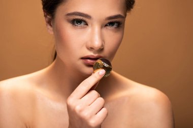 çıplak genç kadın bej izole dudaklar yakınında altın folyo içinde çikolata sikke tutan
