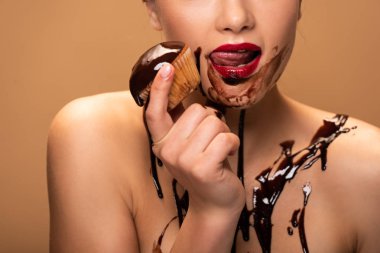 çıplak kadın cilt üzerine çikolata dökülmeleri ile kırmızı dudaklar yalama kısmi görünümü ve bej izole muffin tutarak