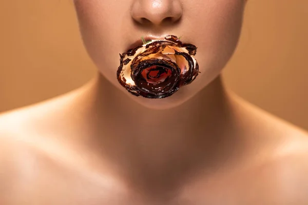 ベージュに隔離された溶けたチョコレートで覆われた口の中にバラを持つ裸の女性のトリミングされたビュー — ストック写真