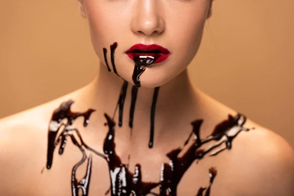 ベージュで隔離された皮膚に赤い唇とチョコレートのこぼれを持つ裸の女性のトリミングビュー — ストック写真