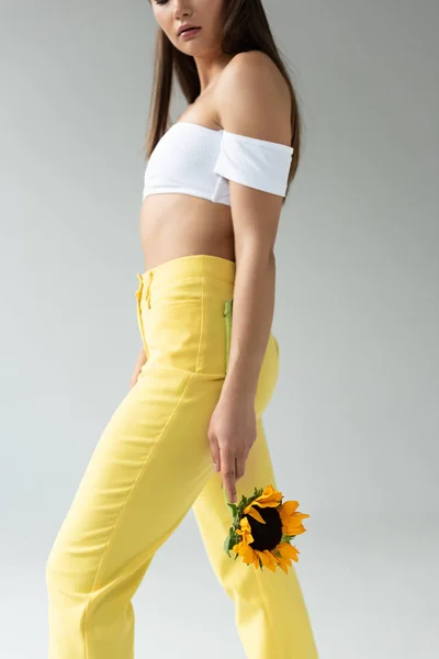 Vista Lateral Mulher Calças Amarelas Posando Com Girassol Isolado Cinza — Fotografia de Stock