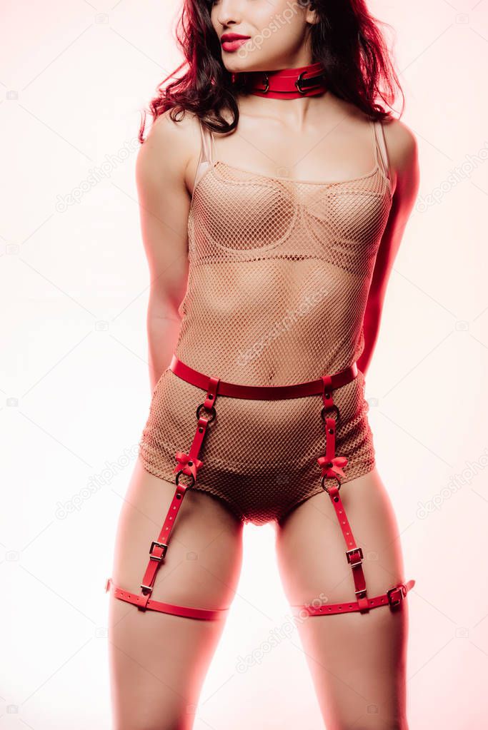 cropped view of sexy young woman in beige lingerie, red collar and swordbelt on light background