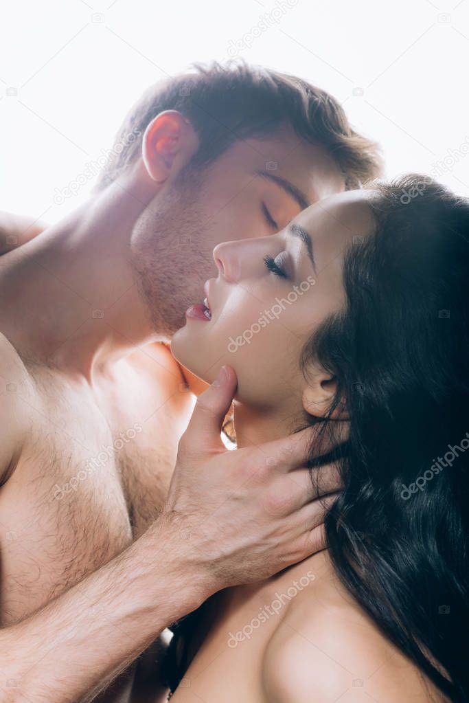 naked young man kissing woman with closed eyes isolated on white