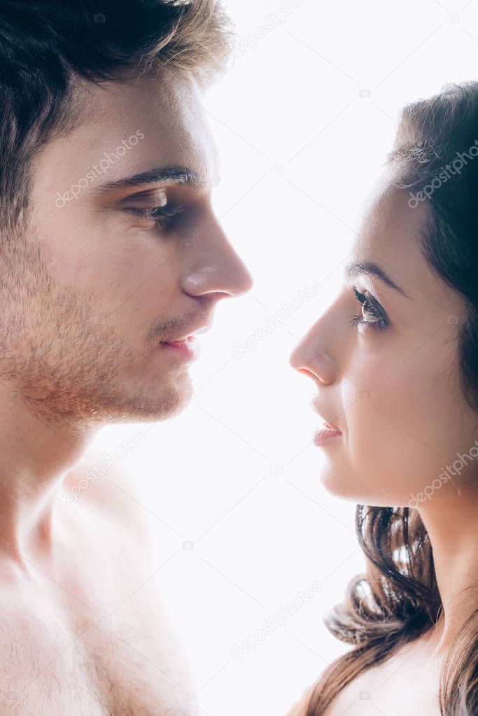 naked young woman and man standing face to face isolated on white