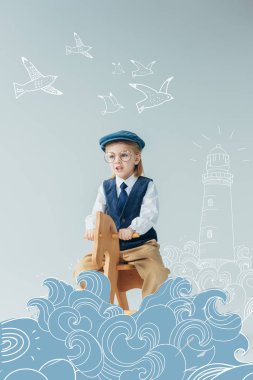 retro yelek ve şapka fantezi deniz feneri, dalgalar ve uçan kuşlar illüstrasyon ile gri arka plan üzerinde sallanan at sürme çocuk