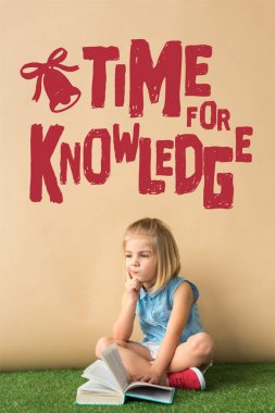 ot halı üzerinde çapraz bacaklar ile oturan ve bilgi yazı için kırmızı zaman ile bej arka plan üzerinde kitap tutan pensive sevimli çocuk