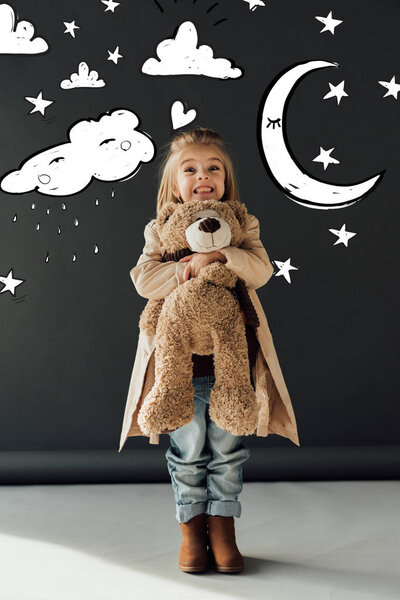 happy and cute child in trench coat and jeans hugging teddy bear on black background with magic moon, stars and rainy cloud illustration
