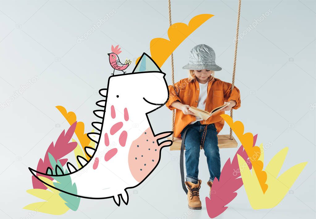 cute kid in jeans and orange shirt sitting on swing and reading book on grey background with fantasy bird and dinosaur illustration