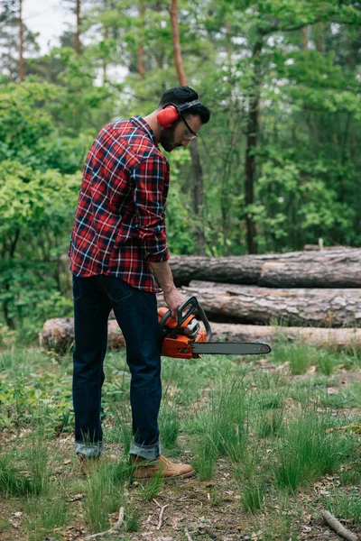 Adult Bearded Man Checkered Shirt Earmuffs Holding Chainsaw Forest — Stock Photo, Image