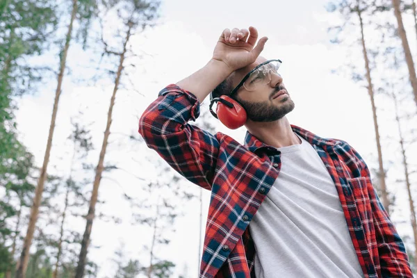 Tired Lumberjack Protective Glasses Holding Hand Head Looking Away Forest — Stock Photo, Image
